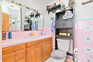 Bathroom with walk in shower, vanity, toilet, and tile walls