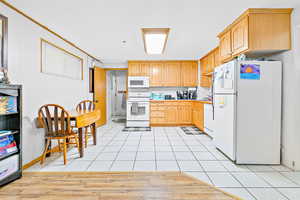 Kitchen with light tile patterned floors, white appliances, and light brown cabinets