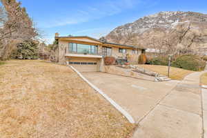 View of front of property featuring a balcony, a garage, a mountain view, and a front lawn