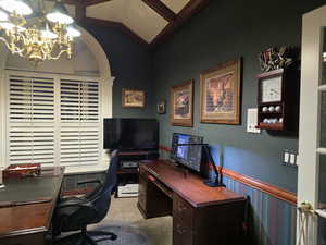 Office area featuring lofted ceiling, carpet floors, and a chandelier