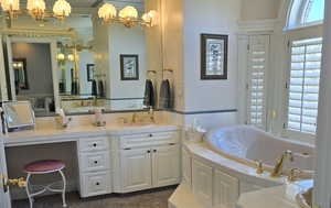 Bathroom with vanity, a washtub, ornamental molding, and an inviting chandelier