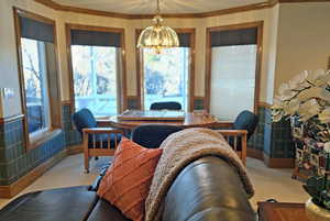 Carpeted dining room with a notable chandelier and ornamental molding