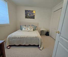 Carpeted bedroom featuring crown molding