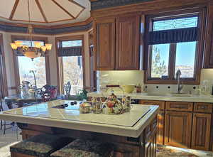 Kitchen featuring hanging light fixtures, tile counters, a kitchen island, decorative backsplash, and a chandelier