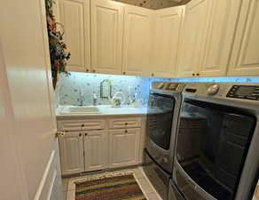 Laundry area featuring cabinets, sink, light tile patterned floors, and independent washer and dryer