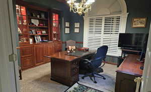 Home office featuring light carpet and a notable chandelier