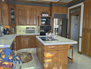 Kitchen with a kitchen island, sink, backsplash, light tile patterned floors, and black appliances