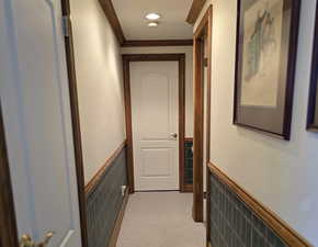 Corridor featuring tile walls, light colored carpet, and ornamental molding