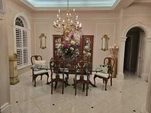 Dining space featuring an inviting chandelier, a tray ceiling, crown molding, and light tile patterned floors. Premium dining table negotiable.