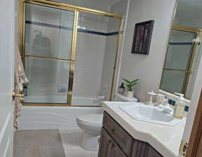 Full bathroom with vanity, tile patterned floors, enclosed tub / shower combo, and toilet