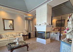 Carpeted living room featuring ornamental molding, vaulted ceiling, and a multi sided fireplace