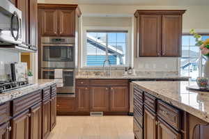 Kitchen with sink, light stone countertops, and appliances with stainless steel finishes