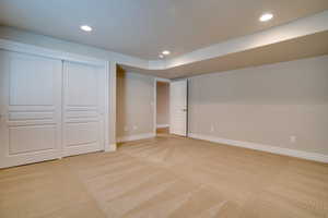 Unfurnished bedroom featuring light colored carpet, a textured ceiling, and a closet