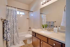 Full bathroom featuring toilet, vanity, shower / bathtub combination with curtain, and tile patterned flooring