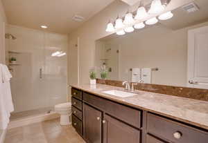 Bathroom with tile patterned flooring, vanity, a shower with shower door, and toilet