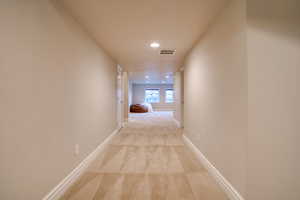 Corridor featuring light colored carpet and a textured ceiling