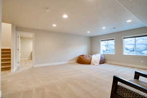 Living area featuring light carpet and a textured ceiling