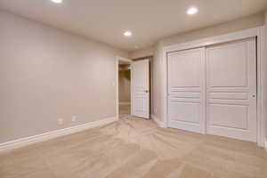 Unfurnished bedroom featuring light colored carpet and a closet