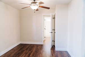 Unfurnished room featuring dark wood-type flooring and ceiling fan