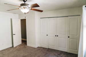 Unfurnished bedroom featuring ceiling fan, dark carpet, and a closet