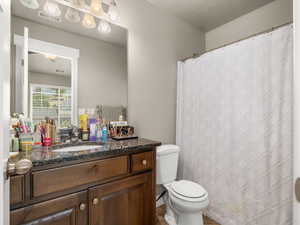 Bathroom with a textured ceiling, toilet, and vanity