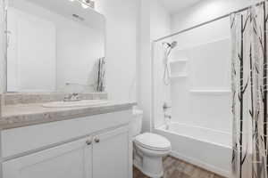 Full bathroom with vanity, hardwood / wood-style flooring, toilet, and shower / bath combo with shower curtain