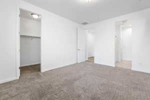 Unfurnished bedroom featuring a spacious closet, light colored carpet, and a closet