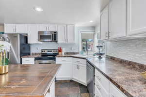 Kitchen featuring sink, decorative backsplash, stainless steel appliances, and white cabinets