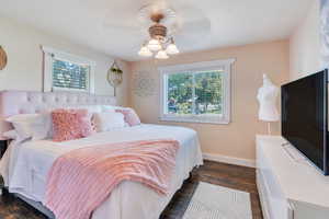 Bedroom featuring dark wood-type flooring, ceiling fan, and multiple windows