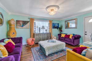 Living room featuring ornamental molding, an inviting chandelier, and dark hardwood / wood-style flooring