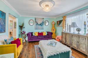 Living room with ornamental molding, a notable chandelier, and dark hardwood / wood-style flooring