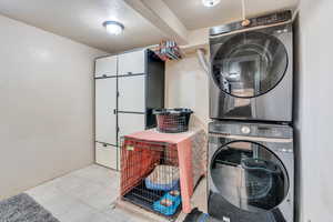 Laundry area featuring stacked washer / dryer and light tile patterned flooring