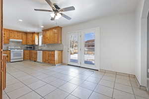 Kitchen with backsplash, white appliances, ceiling fan, and light tile patterned flooring