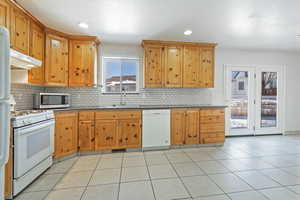 Kitchen with tasteful backsplash, white appliances, sink, and light tile patterned floors