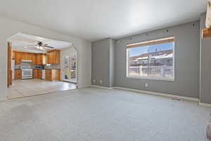 Unfurnished living room with ceiling fan and light colored carpet