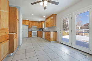 Kitchen featuring sink, white appliances, ceiling fan, light tile patterned flooring, and decorative backsplash