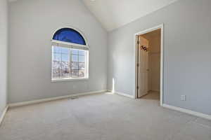 Unfurnished room featuring high vaulted ceiling and light colored carpet