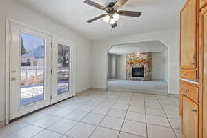 Unfurnished living room featuring ceiling fan, plenty of natural light, light tile patterned floors, and a fireplace