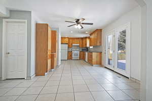 Kitchen featuring sink, decorative backsplash, light tile patterned floors, ceiling fan, and white appliances