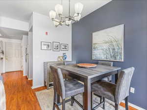 Dining area with hardwood / wood-style floors and an inviting chandelier