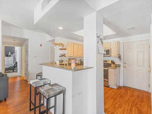 Kitchen with dark stone countertops, a kitchen breakfast bar, light hardwood / wood-style floors, and appliances with stainless steel finishes