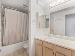 Full bathroom featuring shower / bath combination with curtain, vanity, and toilet