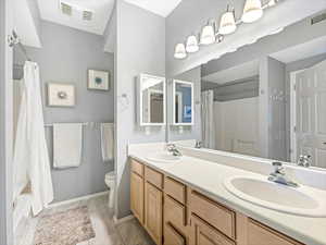 Full bathroom with vanity, shower / tub combo, and toilet