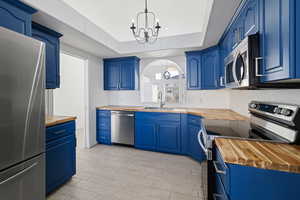 Kitchen featuring stainless steel appliances, sink, butcher block countertops, and hanging light fixtures