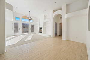 Unfurnished living room featuring a high ceiling, light wood-type flooring, built in features, and a textured ceiling