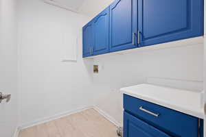 Laundry area with washer hookup, cabinets, and light wood-type flooring