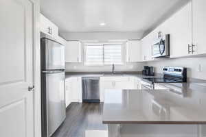 Kitchen featuring dark hardwood / wood-style flooring, sink, white cabinets, and appliances with stainless steel finishes