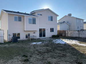 Rear view of house featuring central AC and a lawn