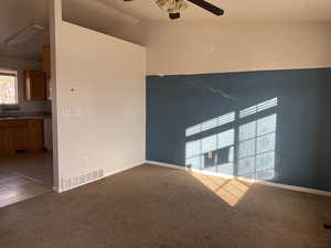 Carpeted spare room featuring ceiling fan, lofted ceiling, and sink