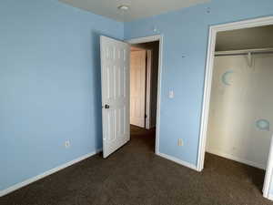 Unfurnished bedroom with dark colored carpet and a closet